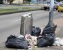 Un bote de basura desbordado, con basura alrededor 
