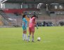 Dos mujeres con uniformes de fútbol en una cancha de fútbol