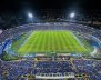 Vista panorámica de un estadio de fútbol. Los hinchas visten prendas azules y el cielo está de noche