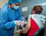 Mujer vacunando a otra mujer de la tercera edad