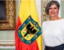 La veedora distrital está al lado de una bandera amarilla y roja con el escudo de Bogotá