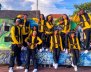 Jóvenes con uniforme amarillo sobre un letrero