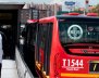 Vista de la parte posterior de un bus de TransMilenio al lado de una estación del mismo servicio.