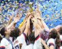 Mujeres de la Selección femenina de Estados Unidos alzan el trofeo del campeonato juntando sus manos.
