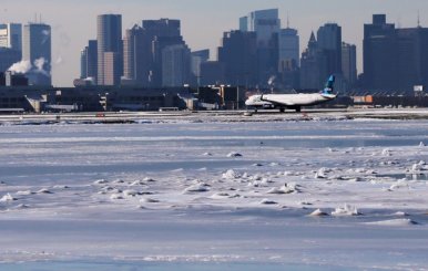 A Jet Blue flight waits to take off from Logan Airport next to the frozen waters of the harbour between Winthrop and Boston