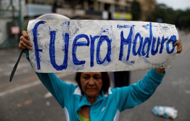 An opposition supporter holds a placard that reads "Maduro out" as she attends a rally against Venezuela's President Maduro in Caracas