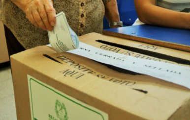Caja de cartón. Una mano introduce un papel verde en ella