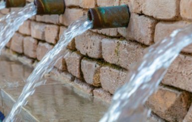 Agua cayendo por tubos de grifería 