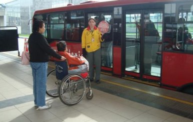 Persona en silla de ruedas subiéndose a un bus rojo de TransMilenio