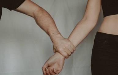 Un hombre apretando con fuerza el brazo de una mujer