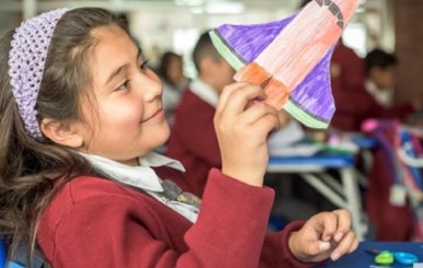 Niña jugando con una nave espacial de papel