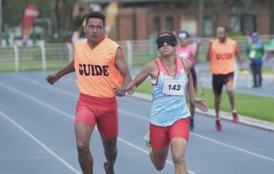 Una atleta y su guía corriendo en una pista de atletismo