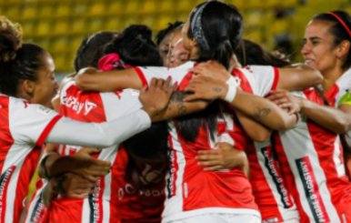 Jugadoras de fútbol de uniforme rojo abrazándose 