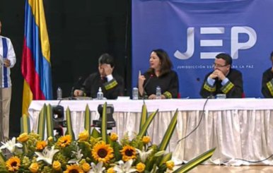 Funcionarios de la JEP sentados en una mesa blanca