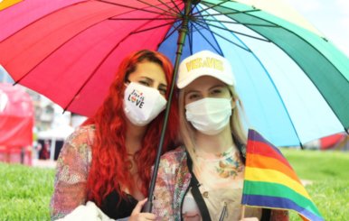 Dos mujeres con tapabocas y bajo una sombrilla miran a la cámara
