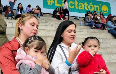 Dos mujeres con niñas alzadas en las rodillas estando en una escalera.