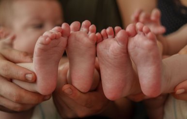 Pies de dos bebés al lado de sus padres