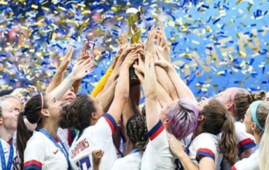 Mujeres de la Selección femenina de Estados Unidos alzan el trofeo del campeonato juntando sus manos.