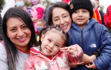Dos mujeres adultas junto a dos niños abrazados y sonriendo 