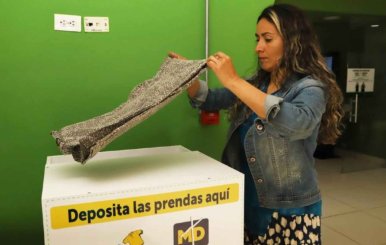 Mujer depositando ropa usada en uno de los contenedores habilitados por la Alcaldía 