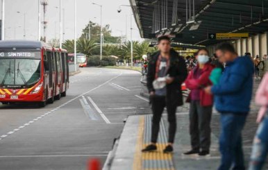 Varias personas es una de las estaciones de TransMilenio esperando su ruta 