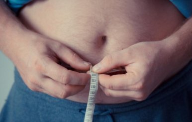 Hombre midiéndose el diámetro de la cintura con una cinta métrica
