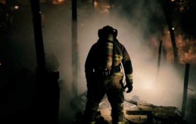 Bombero de espaldas frente a una conflagración recién apagada.