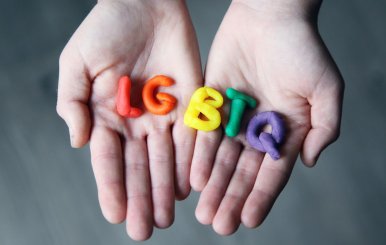 Manos con la palabra LGBTQ hecha de plastilina