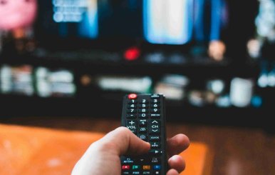 Una persona con un control remoto en la mano a punto de cambiar algo en su televisor