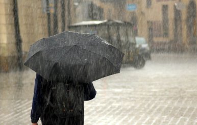 Persona con una sombrilla en la mano bajo la lluvia 