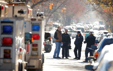 Police gather outside a house in the Brooklyn borough, while they investigate an earlier incident of the reported explosion at the New York Port Authority Bus Terminal in Manhattan, in New York City