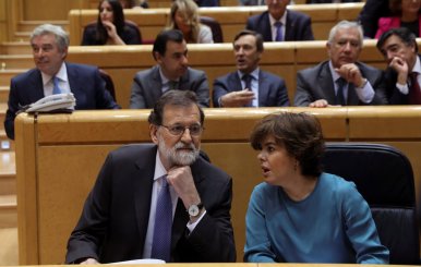 Spain's PM Rajoy listens to Deputy PM Saenz de Santamaria at the start of a debate at the upper house Senate in Madrid