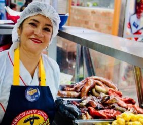 Una mujer con mantel y cofia delante de una mesa llena de fritanga