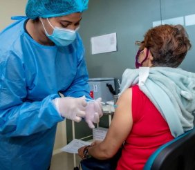 Mujer vacunando a otra mujer de la tercera edad