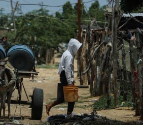 Un hombre cargando unos bidones de agua