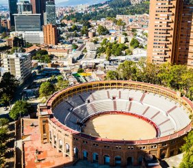 Una plaza de toros con dos torres de edificios detrás