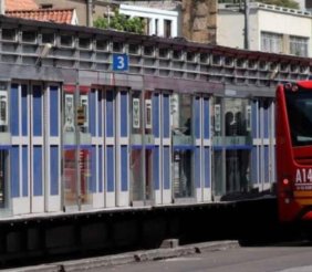 Estación de transMilenio por dentro un pacillo con piso metálico y puertas de cristal a los lados