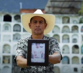 Un hombre sosteniendo un retrato de su hijo en sus manos