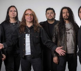 Cuatro hombres vestidos de negro al frente de un fondo gris