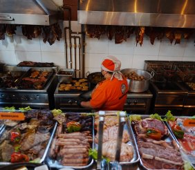 Cocina con una cocinera en el medio y rodeada de diversos ingredientes 