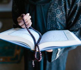 Biblia con rosario sostenidas por unas manos de mujer 