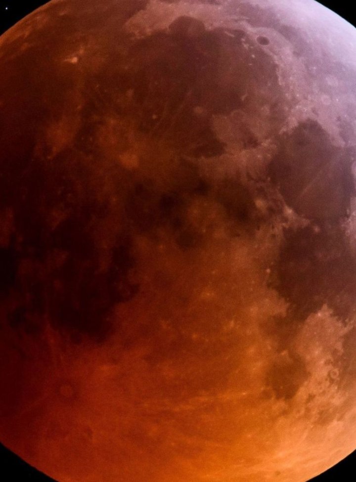 Foto de una luna llena toda de color rojo, sobre un fondo negro
