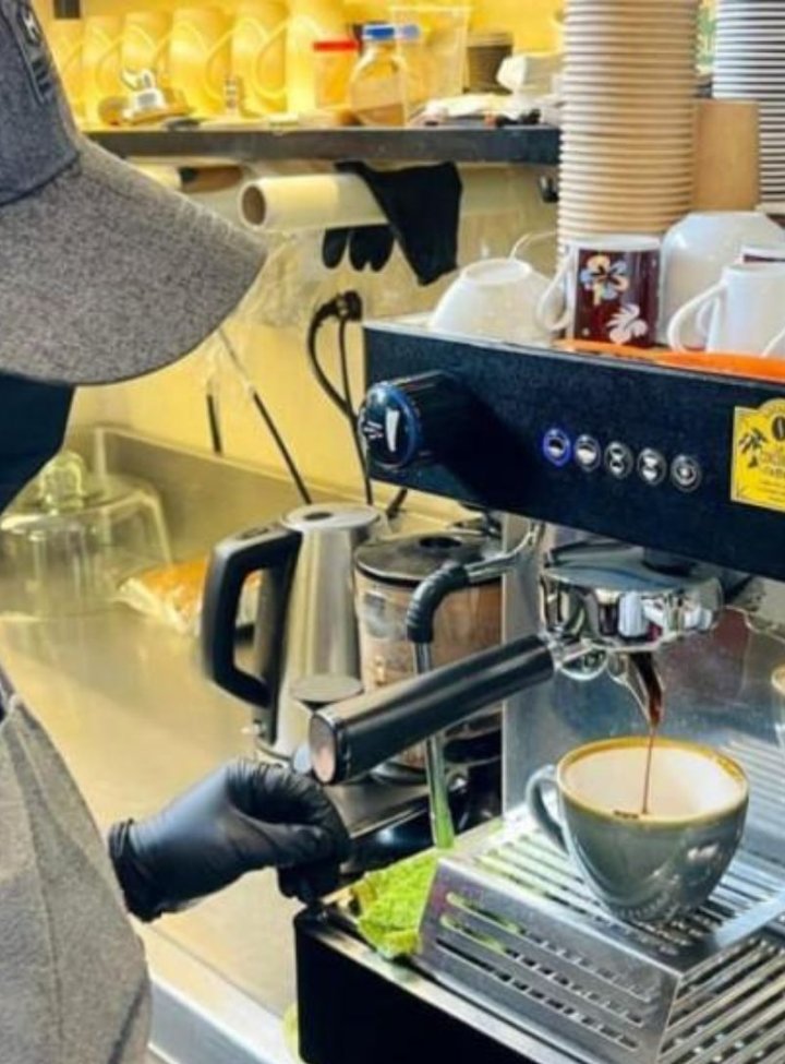 Hombre con mandil y tapabocas preparando café